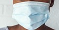 نیلے رنگ کا، ڈسپوزایبل میڈیکل ماسک پہنے خاتون کا کلوز اپ۔